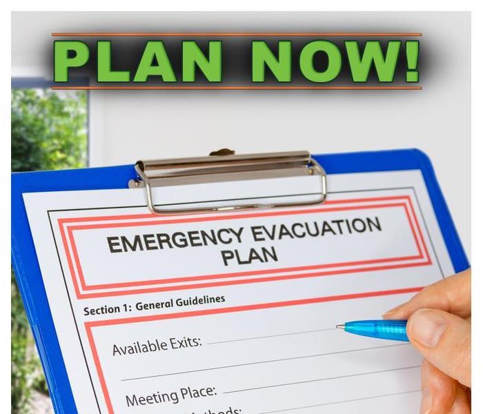 Hand writing an Emergency Evacuation Plan on clipboard beside Exit Door